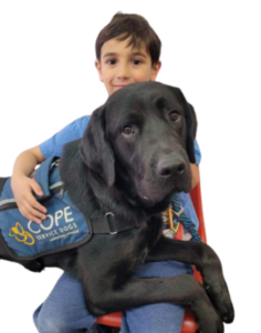 Student with black lab on his lap wearing a COPE Service Dog Vest